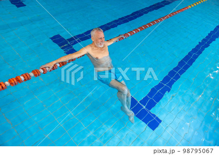Gray-haired bearded swimmer looking contented at the swimming pool Gray-haired bearded swimmer looking contented at the swimming pool 98795067