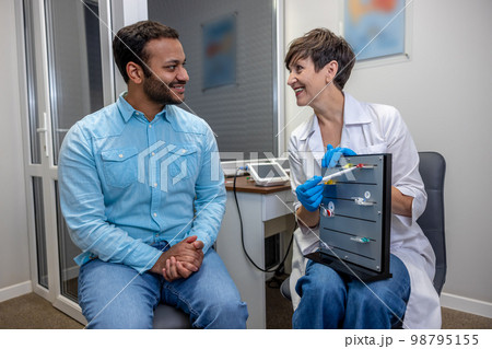 ENT doctor demonstrating hearing aid models to the patient ENT doctor demonstrating hearing aid models to the patient 98795155