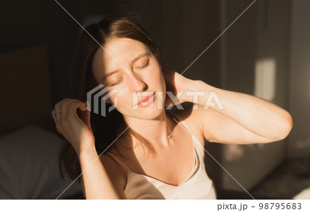 Portrait woman waking up in her bed, she is smiling and stretching. Happy young woman greets new sunny day Portrait woman waking up in her bed, she is smiling and stretching. Happy young woman greets new sunny day 98795683