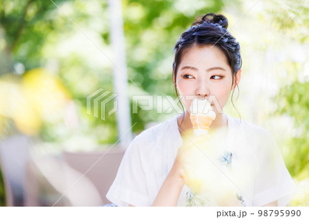 笑顔でソフトクリームを食べる若い女の子 98795990