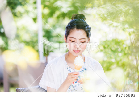 笑顔でソフトクリームを食べる若い女の子 笑顔でソフトクリームを食べる若い女の子 98795993
