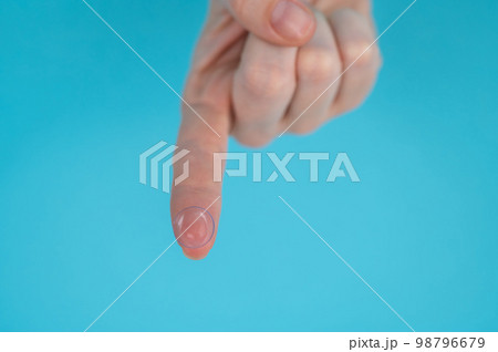 Woman holding contact lens on blue background.  98796679