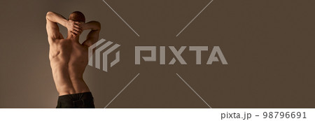 Back view photo of shirtless young man in pants over grey studio background. Strong, relief, muscular body, back. Men's health, beauty and sportive lifestyle 98796691