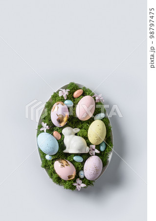 Easter composition in oval plate with painted eggs, rabbit, green decorative moss. Easter composition in oval plate with painted eggs, rabbit, green decorative moss. 98797475