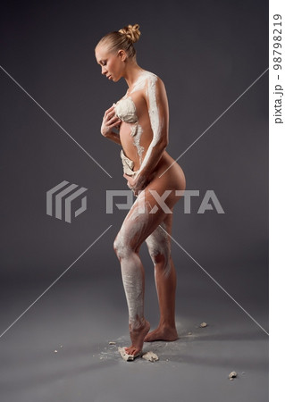 Naked woman covered with clay mask on body Naked woman covered with clay mask on body 98798219