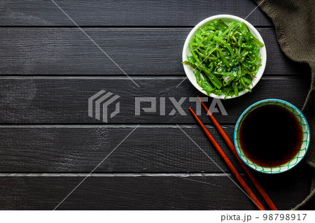 Green seaweed. Japanese wakame salad in bowl and soy sauce. Top view. 98798917