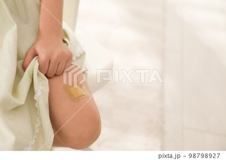 Girl with sticking plaster on leg indoors, closeup 98798927