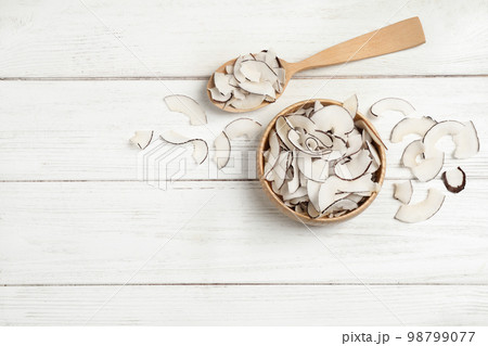 Tasty coconut chips on white wooden table, flat lay. Space for text 98799077