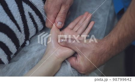 A masseur massages the wrists of a girl. 98799642
