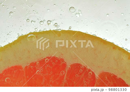 Slice of red grapefruit in water on white background. Grapefruit close-up in liquid with bubbles. Slice of red ripe grapefruit in water. Macro image of fruit in water 98801330