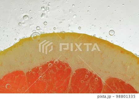 Close-up of fresh grapefruit slice on white background. Slice of red grapefruit in sparkling water on white background, close-up. Horizontal image Close-up of fresh grapefruit slice on white background. Slice of red grapefruit in sparkling water on white background, close-up. Horizontal image 98801335