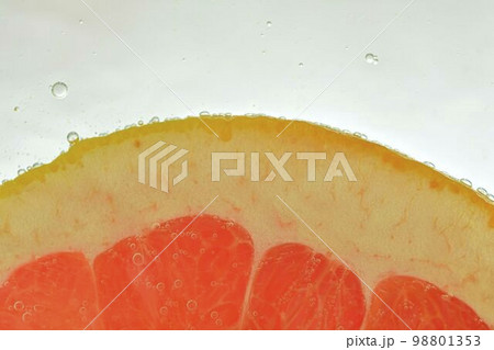 Close-up of fresh grapefruit slice on white background. Slice of red grapefruit in sparkling water on white background, close-up. Horizontal image Close-up of fresh grapefruit slice on white background. Slice of red grapefruit in sparkling water on white background, close-up. Horizontal image 98801353