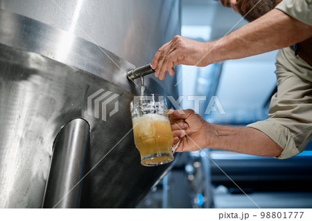 Closeup busy brewery engineer pouring beer to test quality 98801777