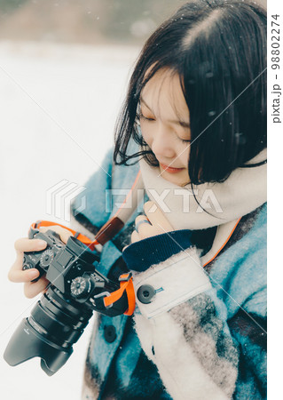 雪の中若い女性がカメラを持っている写真 雪の中若い女性がカメラを持っている写真 98802274