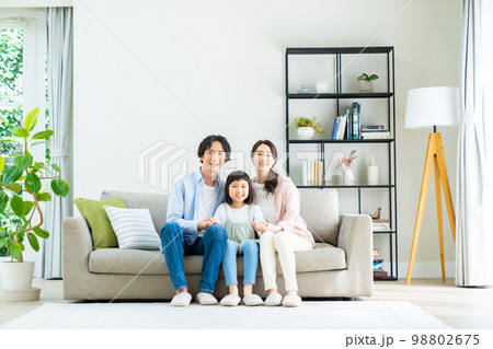 リビングでくつろぐ若い家族 98802675