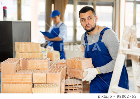 Repairman carrying bricks in construction site 98802765