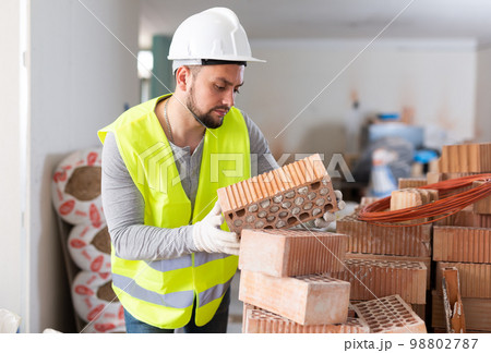 Construction worker checking bricks at renovating object Construction worker checking bricks at renovating object 98802787