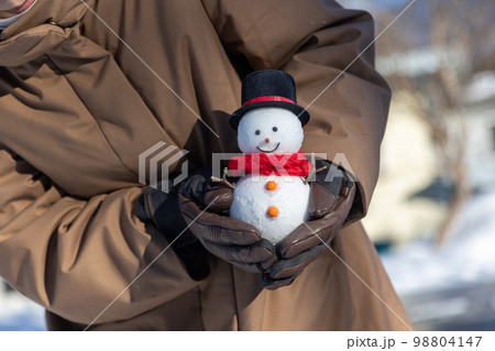 シルクハットの雪だるまを持つ人物 98804147