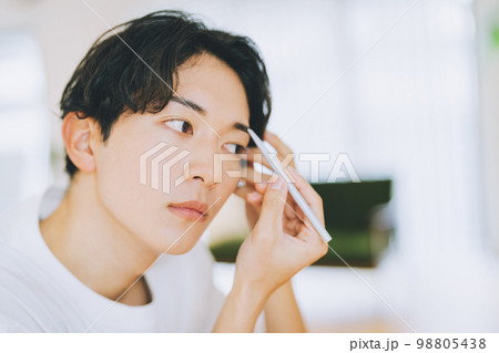 アイブロウペンシルを使って眉毛を書く男性 98805438