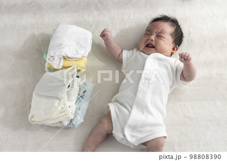 起きている赤ちゃんと畳んだ子供服（0歳2か月、日本人、男の子） 98808390