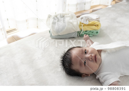 起きている赤ちゃんと畳んだ子供服(0歳2か月、日本人、男の子) 起きている赤ちゃんと畳んだ子供服(0歳2か月、日本人、男の子) 98808391