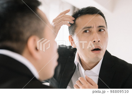 頭皮・白髪を気にして鏡を見る男性 98809510
