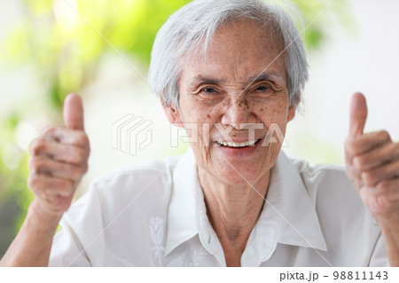 Happy asian senior woman give thumb raised up,feel fit and healthy,Smiling old elderly showing two thumbs up gesture at her good physical and mental health,health conscious,healthiness,medical concept 98811143