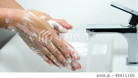 Hands of woman wash their hands in a sink with foam to wash the skin and water flows through the hands. Concept of health, cleaning and preventing germs and coronavirus from contacting hands Hands of woman wash their hands in a sink with foam to wash the skin and water flows through the hands. Concept of health, cleaning and preventing germs and coronavirus from contacting hands 98811160