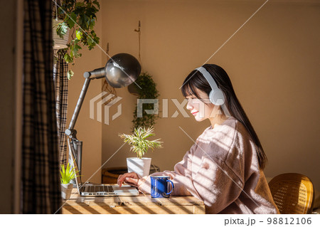 音楽を聴きながらパソコンを使う女性 98812106