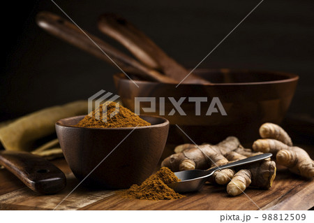 木のテーブルに秋ウコンの根茎とターメリックパウダー 98812509