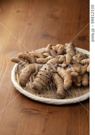 木のテーブルの上に竹笊と秋ウコンの根茎 木のテーブルの上に竹笊と秋ウコンの根茎 98812530