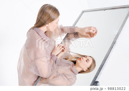 Self-realization portrait woman in mirror image. Unusual strange pretty woman Self-realization portrait woman in mirror image. Unusual strange pretty woman 98813022