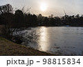 薄氷が張った水面と風車のある景色 98815834
