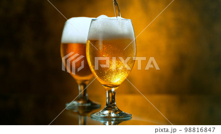 Freshly brewed beer in a pint on orange gradient background, close-up Freshly brewed beer in a pint on orange gradient background, close-up 98816847