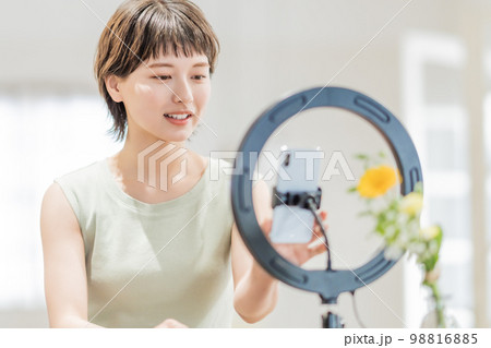 開放的な部屋で動画配信をするワンピース姿の若い女性 開放的な部屋で動画配信をするワンピース姿の若い女性 98816885