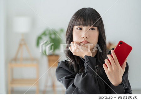 スマホを持って物思いに耽る女子高生 98818030