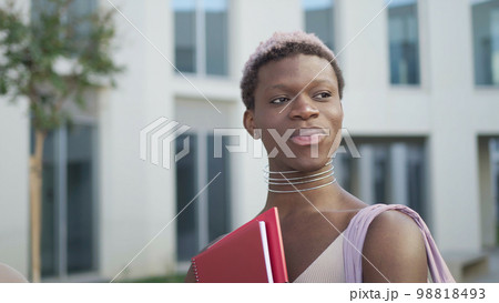 Content queer black man with folder on street 98818493