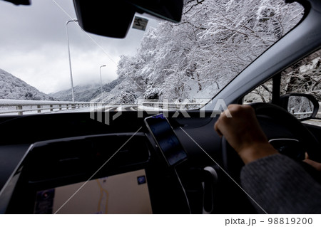 雪が積もっている道路を運転している自動車の運転席と外の冬景色 98819200