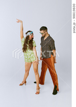 Attraction. Pretty young girl and handsome man in stylish retro clothes dancing disco dance isolated over grey studio background. American culture, hobby 98819600