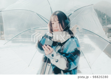 雪の中若い女性がスマホで音楽を聴いてる写真 雪の中若い女性がスマホで音楽を聴いてる写真 98820280