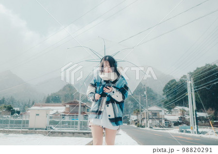 雪の中若い女性がスマホで音楽を聴いてる写真 雪の中若い女性がスマホで音楽を聴いてる写真 98820291