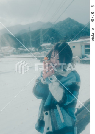 雪の中若い女性が暖かい飲み物を持っている写真 98820919