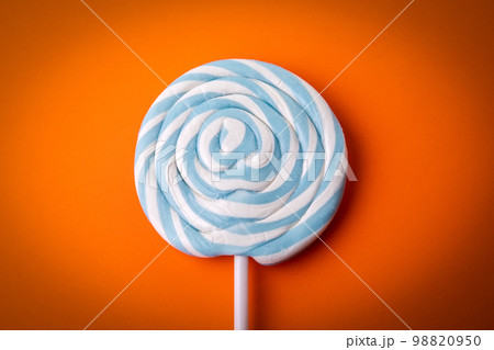 Blue and white candy on a stick, lollipop. Orange background Blue and white candy on a stick, lollipop. Orange background 98820950