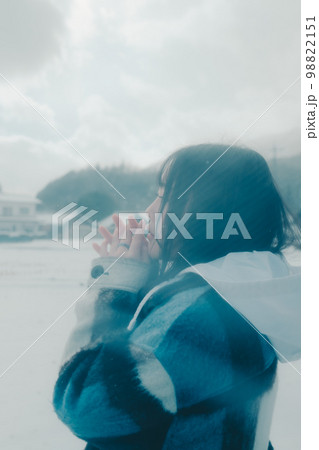 雪の中若い女性が傘をさしている写真 98822151