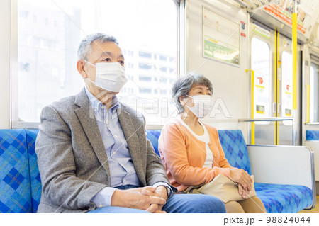 電車でマスクをつけるシニア男女 98824044