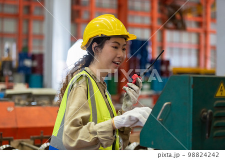 happy smile women engineer holding walkie talkie quality control machine standing at factory happy smile women engineer holding walkie talkie quality control machine standing at factory 98824242