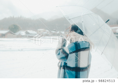 雪の中若い女性が音楽を聴いてる写真 98824513