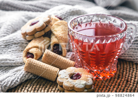 A cup of red tea and cookies on a blurred background with a knitted element. 98824864