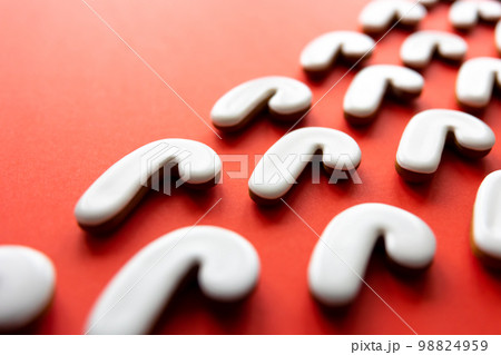 A lot of gingerbread candy cane shaped cookies on a red background. 98824959