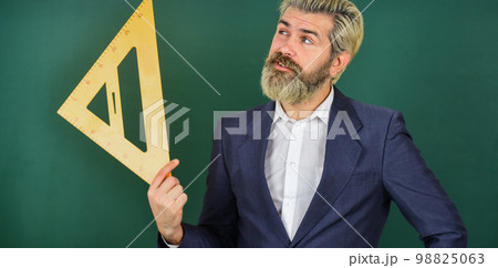 study mathematics lesson. use in architecting and geometry. bearded man engineer in suit. angle measure in physics. math teacher use triangle ruler. back to school. precision measurement study mathematics lesson. use in architecting and geometry. bearded man engineer in suit. angle measure in physics. math teacher use triangle ruler. back to school. precision measurement 98825063
